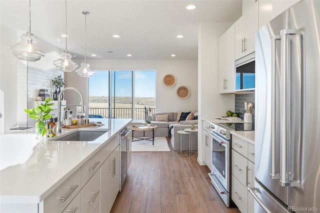 kitchen with pendant lighting, light countertops, appliances with stainless steel finishes, open floor plan, and a sink