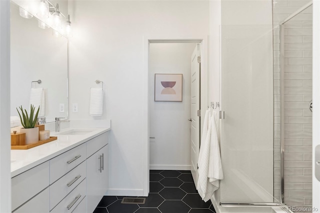 full bathroom with double vanity, a sink, a shower stall, baseboards, and tile patterned floors