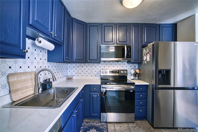 kitchen with light countertops, a sink, stainless steel appliances, and blue cabinetry