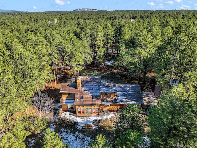 aerial view of property and surrounding area featuring a heavily wooded area
