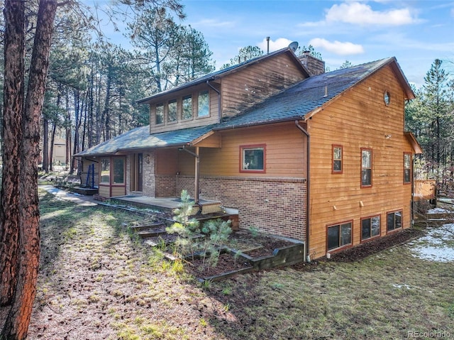 view of property exterior featuring a chimney and brick siding
