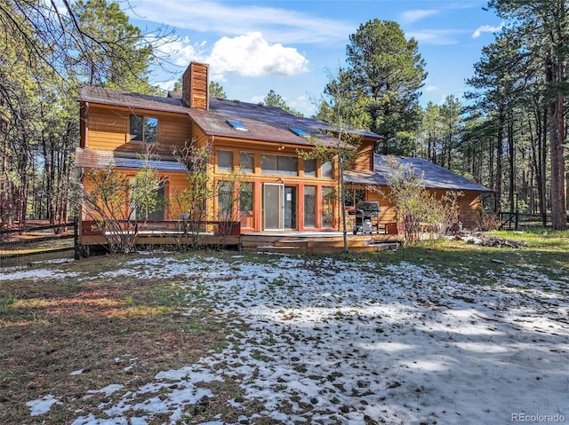 rear view of property with a chimney and a deck