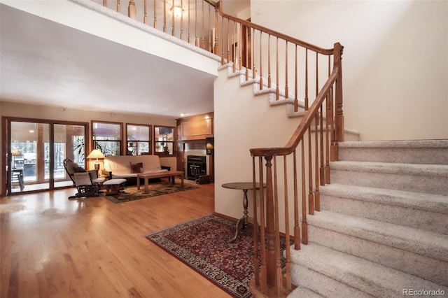 stairs with wood finished floors and a fireplace
