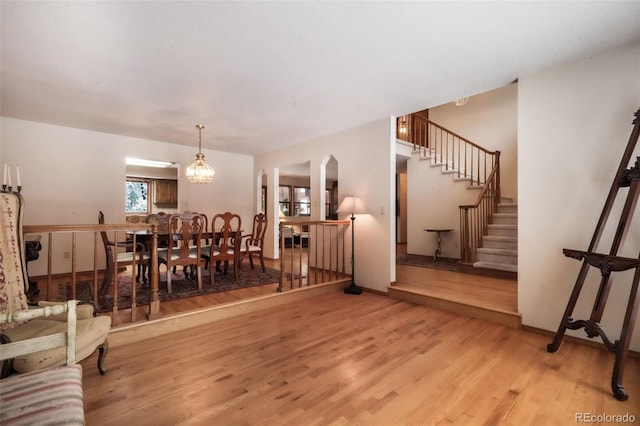 living room with light wood-style floors, stairs, and arched walkways