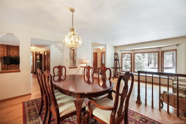 dining area with stairs, light wood-style floors, baseboards, and a chandelier