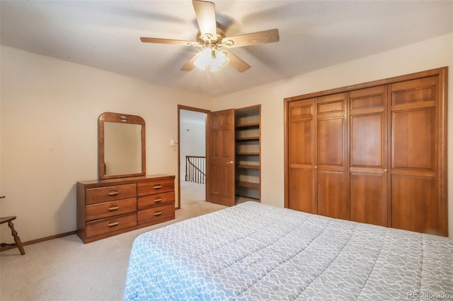 bedroom featuring light colored carpet, baseboards, a ceiling fan, and two closets