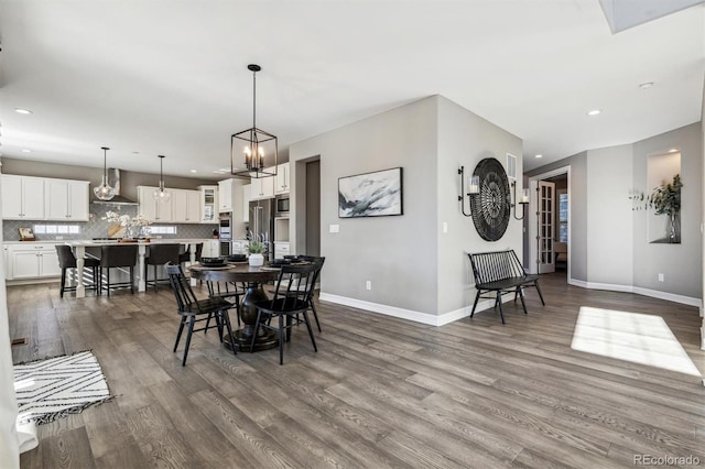 dining room featuring dark wood-type flooring, recessed lighting, baseboards, and an inviting chandelier