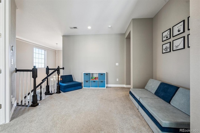 living area featuring carpet, visible vents, baseboards, and an upstairs landing