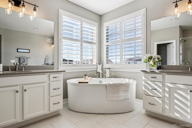 full bath featuring a soaking tub, two vanities, a sink, and tile patterned floors