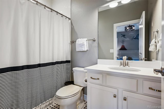 full bathroom with a textured wall, vanity, toilet, and ensuite bathroom