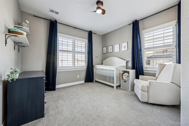 bedroom with a crib, baseboards, visible vents, and light colored carpet