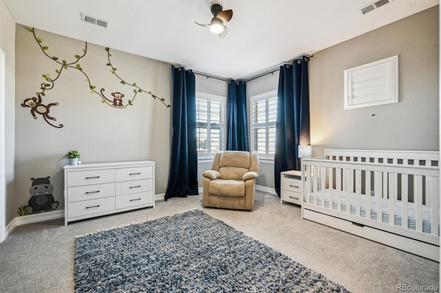 bedroom featuring a nursery area, visible vents, and light carpet