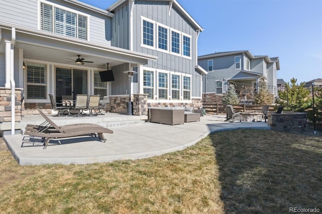 rear view of property with stone siding, ceiling fan, board and batten siding, and a patio