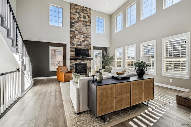 21854 Tyrolite Ave, Parker, CO 80138 - living area with wood finished floors, a towering ceiling, baseboards, a stone fireplace, and stairway