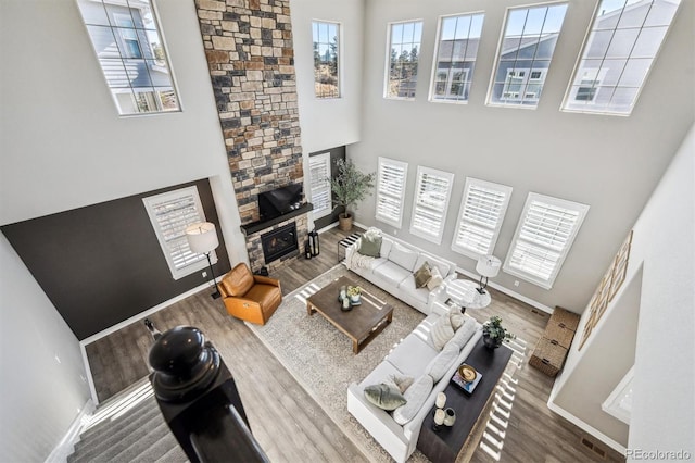 21854 Tyrolite Ave, Parker, CO 80138 - living area featuring wood finished floors, a towering ceiling, a stone fireplace, and baseboards