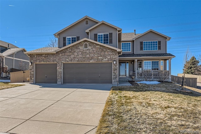 traditional home with a porch, an attached garage, fence, driveway, and stone siding