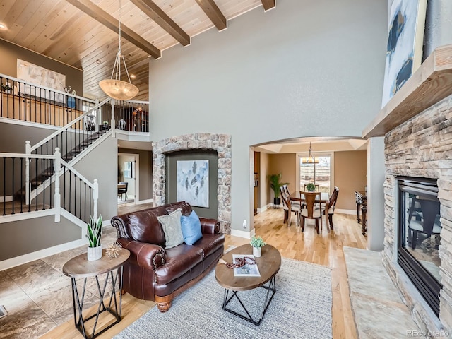 living area featuring wood ceiling, an inviting chandelier, stairs, a high ceiling, and a fireplace