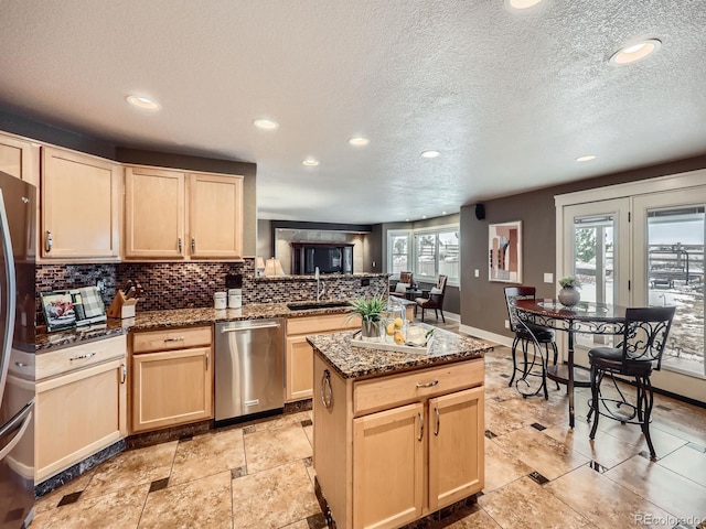 kitchen with tasteful backsplash, stainless steel appliances, a sink, and light brown cabinetry