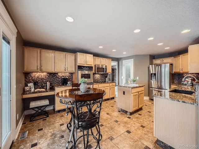 kitchen with light brown cabinets, stainless steel appliances, and a sink