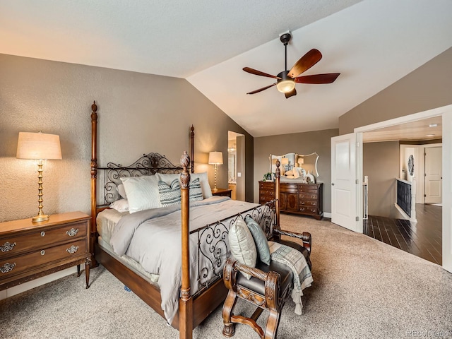 bedroom featuring a textured wall, carpet floors, wood finished floors, a ceiling fan, and vaulted ceiling