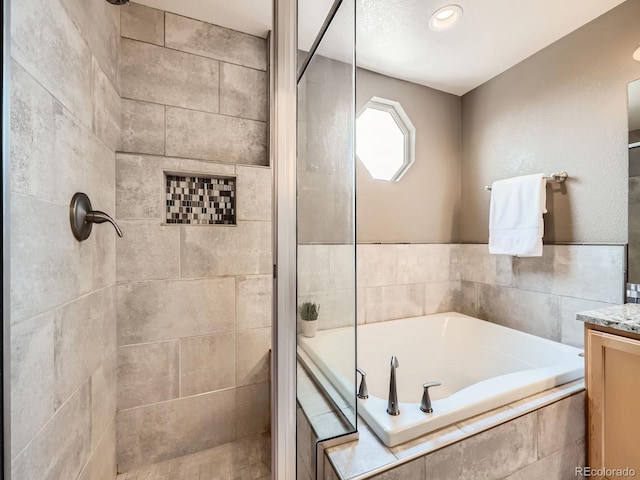 full bathroom featuring a stall shower, a garden tub, and vanity