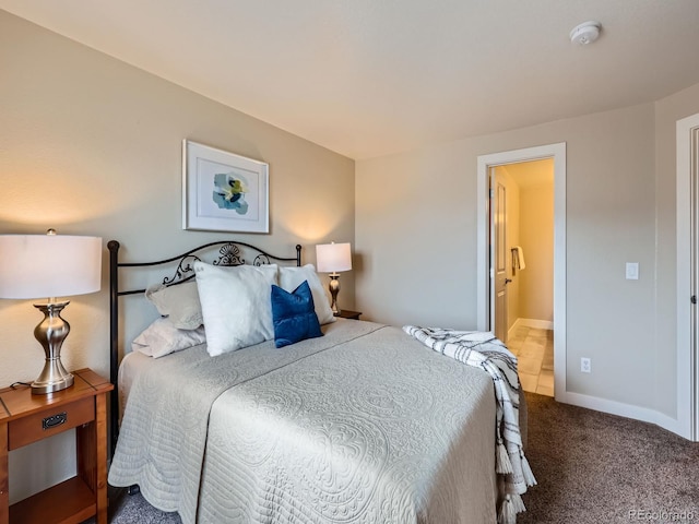 carpeted bedroom with ensuite bathroom and baseboards