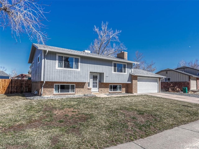 bi-level home with a garage, brick siding, a chimney, and fence