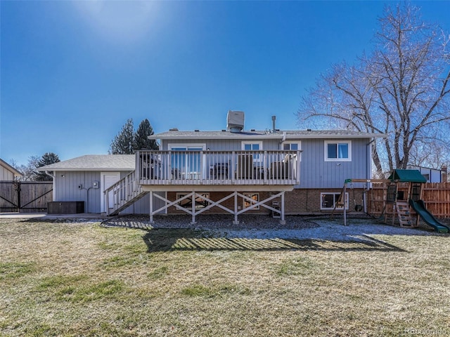 rear view of property with a yard, a playground, fence, and a wooden deck