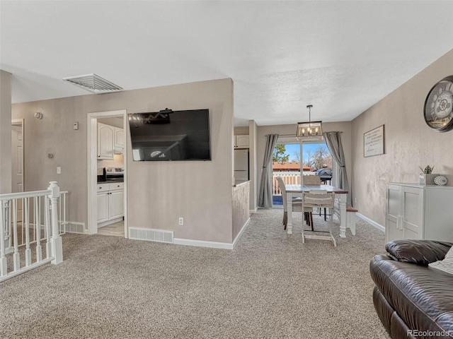 living area featuring baseboards, an inviting chandelier, visible vents, and light colored carpet