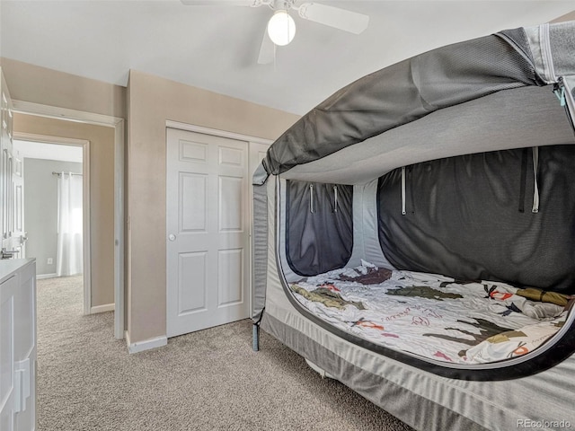 bedroom with ceiling fan, baseboards, and light colored carpet