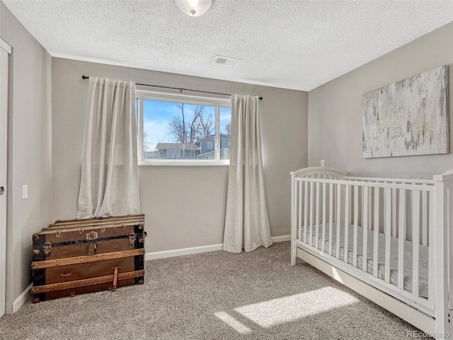 carpeted bedroom featuring a crib, visible vents, baseboards, and a textured ceiling