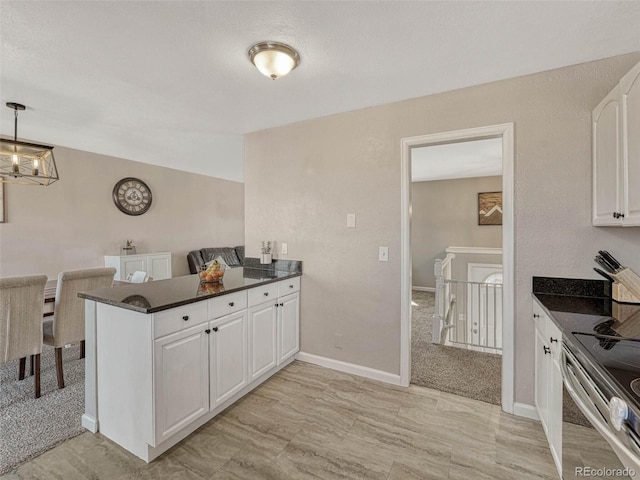 kitchen with a chandelier, a peninsula, baseboards, white cabinets, and electric stove