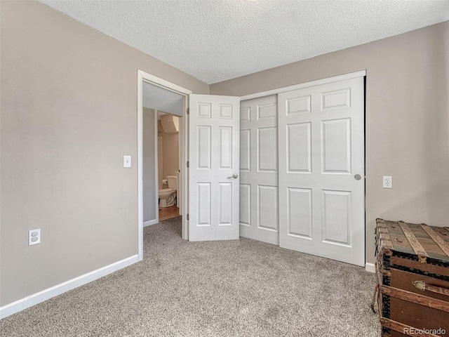 carpeted bedroom featuring a textured ceiling, a closet, and baseboards