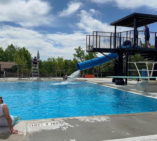 community pool with fence and a water slide