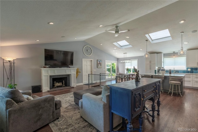 6760 S Depew St, Littleton, CO 80128 - living room with lofted ceiling, dark wood finished floors, a skylight, a fireplace with raised hearth, and recessed lighting