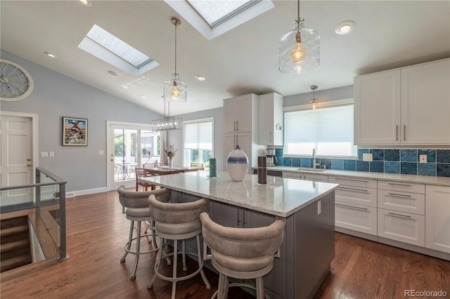 6760 S Depew St, Littleton, CO 80128 - kitchen featuring a skylight, vaulted ceiling, plenty of natural light, a kitchen island, and white cabinets