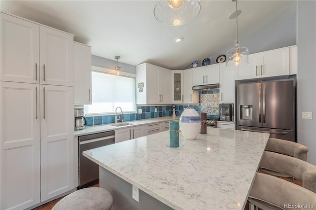 6760 S Depew St, Littleton, CO 80128 - kitchen featuring stainless steel appliances, a breakfast bar area, decorative backsplash, under cabinet range hood, and white cabinetry