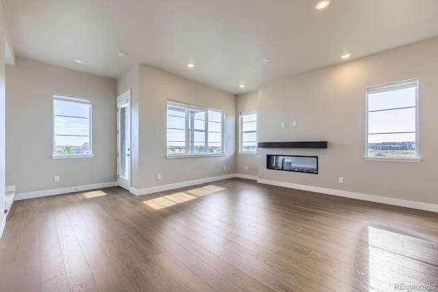 9436 E 57h Ave, Denver, CO 80238 - unfurnished living room featuring a glass covered fireplace, wood finished floors, and recessed lighting