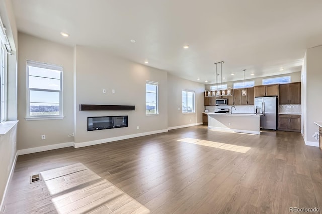 9436 E 57h Ave, Denver, CO 80238 - unfurnished living room with recessed lighting, dark wood-style flooring, and a glass covered fireplace