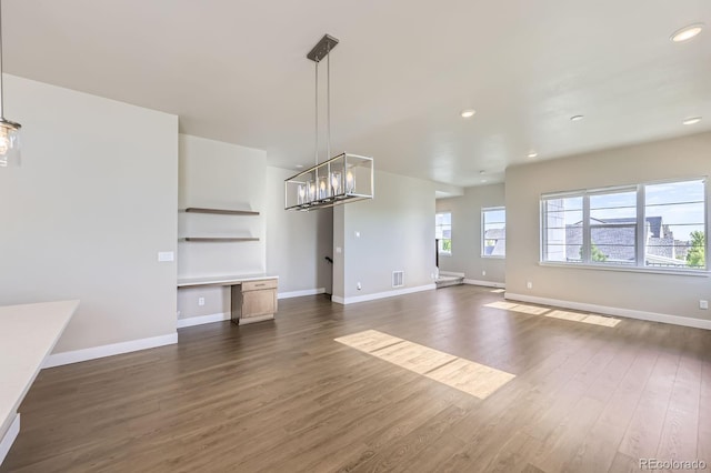 9436 E 57h Ave, Denver, CO 80238 - unfurnished living room with dark wood finished floors, recessed lighting, a chandelier, built in features, and a desk