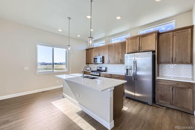 9436 E 57h Ave, Denver, CO 80238 - kitchen featuring stainless steel appliances, tasteful backsplash, a kitchen island with sink, healthy amount of natural light, and recessed lighting