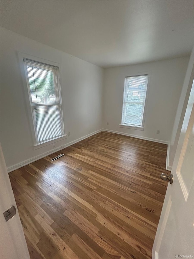 3000 S Sherman St, Englewood, CO 80113 - unfurnished room featuring wood finished floors, plenty of natural light, and baseboards