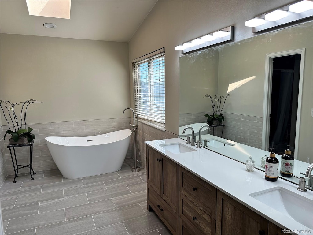 8661 Snowbrush Ln, Highlands Ranch, CO 80126 - bathroom with tile walls, double vanity, a freestanding tub, a skylight, and wainscoting