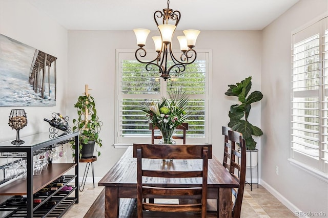 dining space with a chandelier, baseboards, and light tile patterned floors