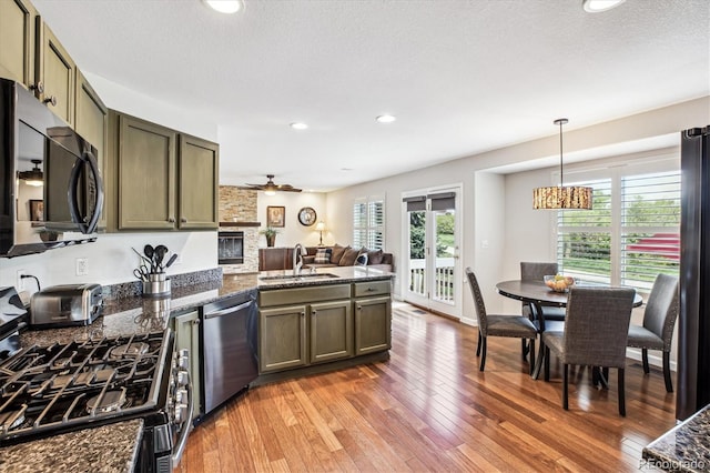 kitchen featuring dishwasher, range with gas stovetop, a sink, a peninsula, and light wood-style floors