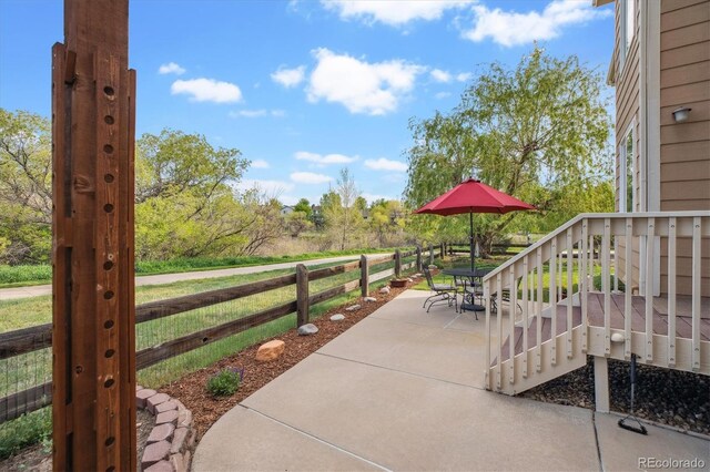 view of patio with outdoor dining area, fence, and stairs