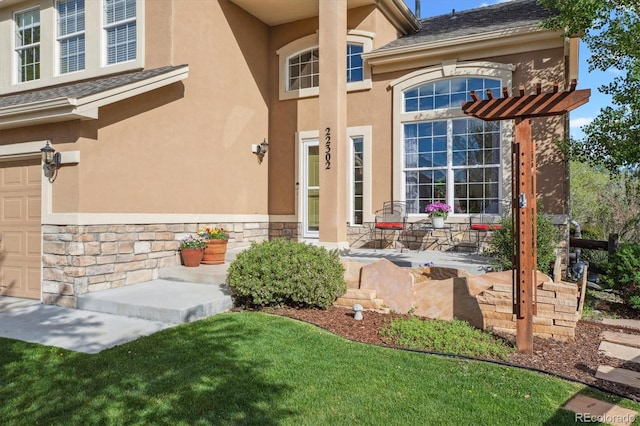 doorway to property featuring stucco siding, stone siding, an attached garage, and a porch