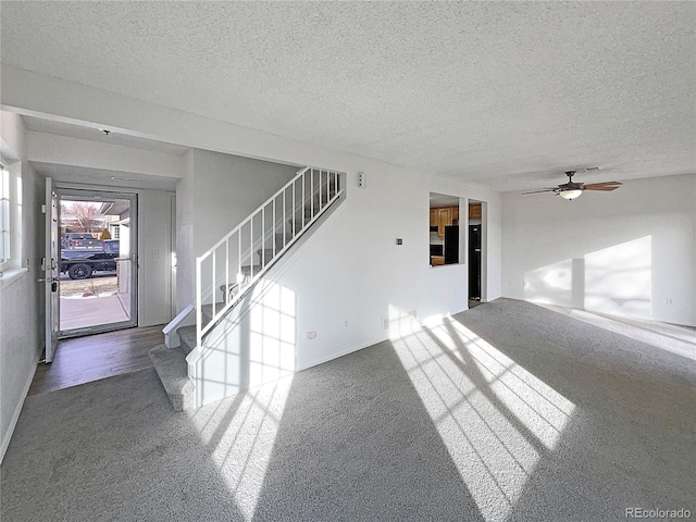 unfurnished living room featuring ceiling fan, dark carpet, and a textured ceiling