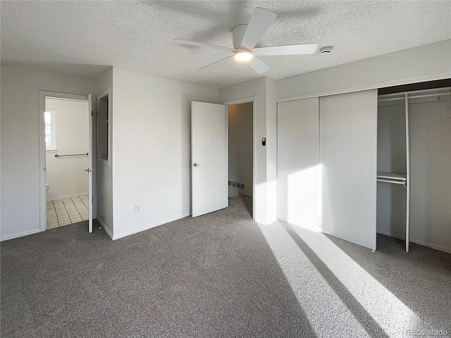 unfurnished bedroom featuring connected bathroom, dark carpet, a closet, and a textured ceiling