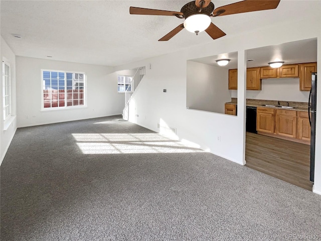 unfurnished living room with sink, carpet floors, and ceiling fan